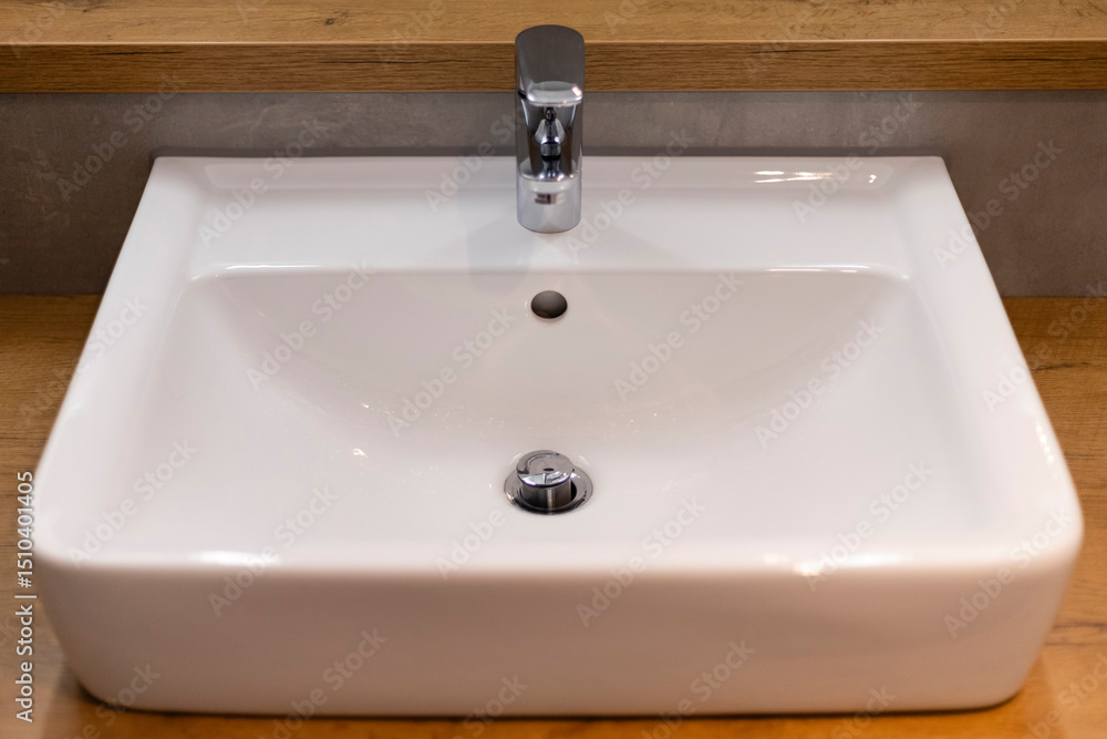 A stylish bathroom sink features a smooth, rectangular design, complemented by a polished faucet. The sink is set on a natural wood countertop, creating a contemporary look and simple elegance A stylish bathroom sink features a smooth, rectangular design, complemented by a polished faucet. The sink is set on a natural wood countertop, creating a contemporary look and simple elegance