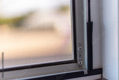 Sunlight streams through a fine mesh window screen, creating a warm and inviting indoor ambiance. The screen's details offer protection from flies while allowing light to filter in