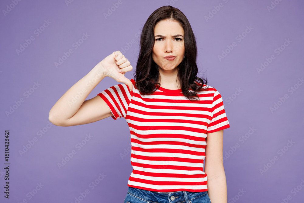 Young sad displeased Caucasian woman she wear red striped t-shirt casual clothes showing thumb down dislike gesture isolated on plain pastel light purple background studio portrait. Lifestyle concept. Young sad displeased Caucasian woman she wear red striped t-shirt casual clothes showing thumb down dislike gesture isolated on plain pastel light purple background studio portrait. Lifestyle concept.