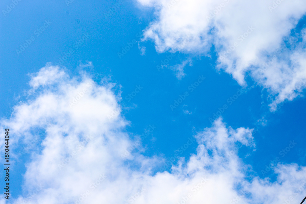 Obraz premium Bright Blue Sky with Soft White Clouds on a Clear Sunny Day – Peaceful Natural Background for Weather, Travel, and Outdoor Concepts