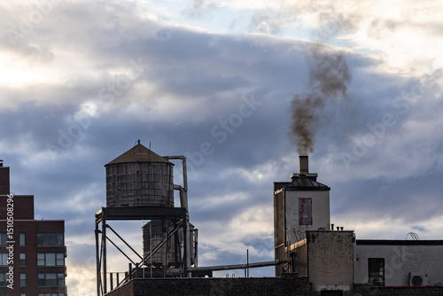 New York, New York, USA A residential house, a rooftop water tank, and a smokestack with smoke.