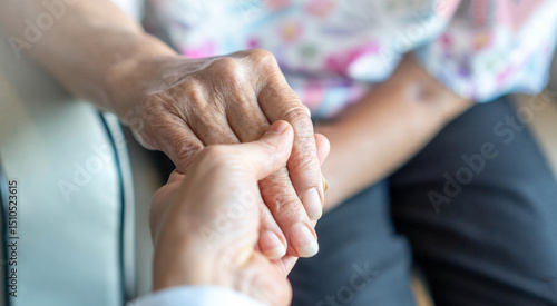 Elderly female hand holding hand of young caregiver at nursing home.Geriatric doctor or geriatrician concept. Doctor physician hand on happy elderly senior patient to comfort in hospital examination