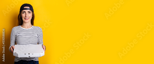 smiling young woman pizza delivery man holding hot fresh pizza on yellow background. Banner
