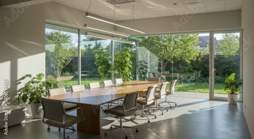 Sunlit conference room with large windows overlooking a lush green garden. Modern design with wooden table and gray chairs