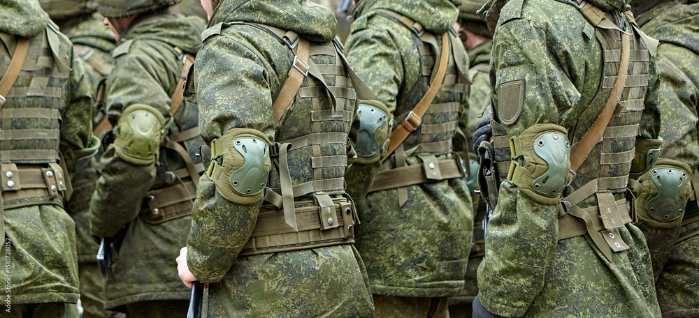 Fototapeta premium Soldiers in tactical gear parade during a military event in a city square on a bright afternoon
