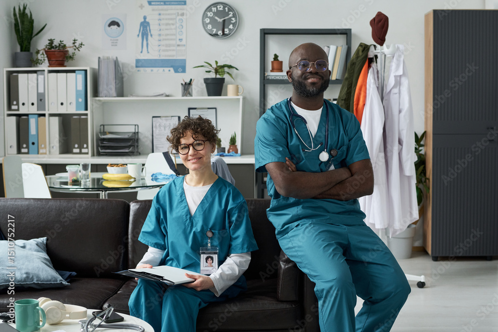 custom made wallpaper toronto digitalPortrait of two medical professionals sitting in office, one male and one female, both smiling and wearing scrubs, medical posters and equipment visible in background