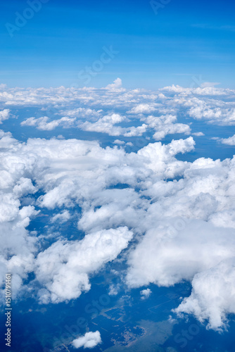 View of the blue sky with white clouds from an airplane window at high altitude