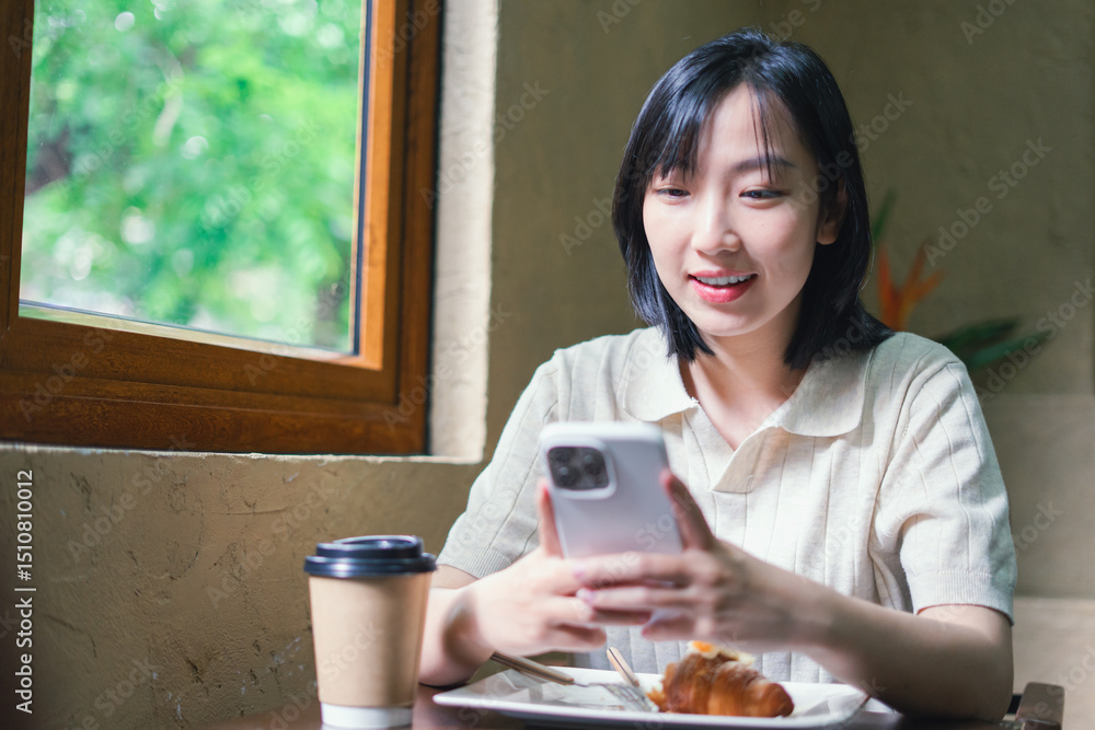 Young woman enjoying breakfast while using smartphone in a cozy cafe setting surrounded by greenery Young woman enjoying breakfast while using smartphone in a cozy cafe setting surrounded by greenery