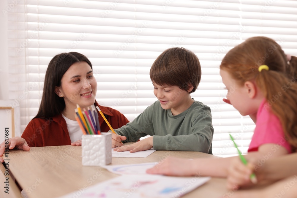 Woman teaching kids to draw at painting lesson indoors Woman teaching kids to draw at painting lesson indoors