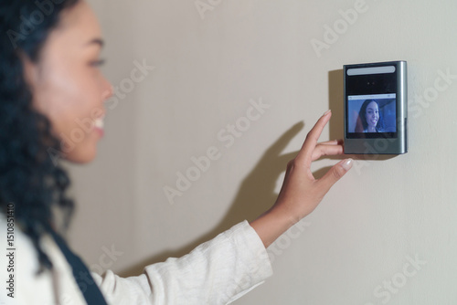 portrait headshot young female african company employee with curly hair standing at time attendance scanner,focus at scanner machine