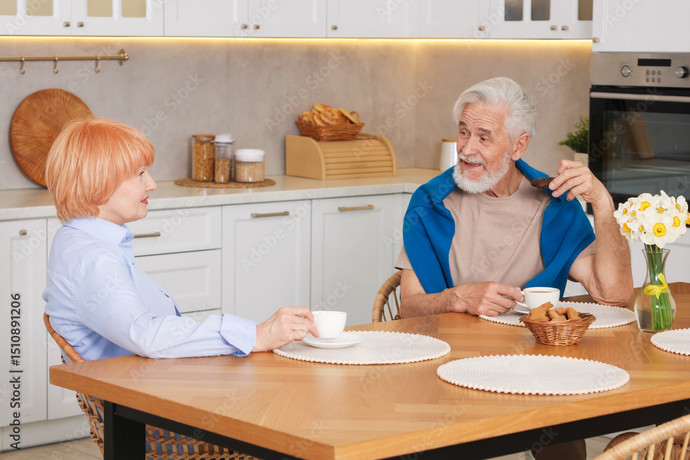 Obraz premium Lovely senior couple having breakfast together at wooden table in kitchen