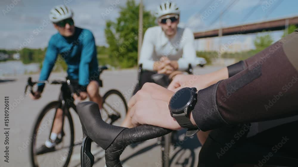 Sportsman with wristwatch holds handlebar near friends on road Sportsman with wristwatch holds handlebar near friends on road