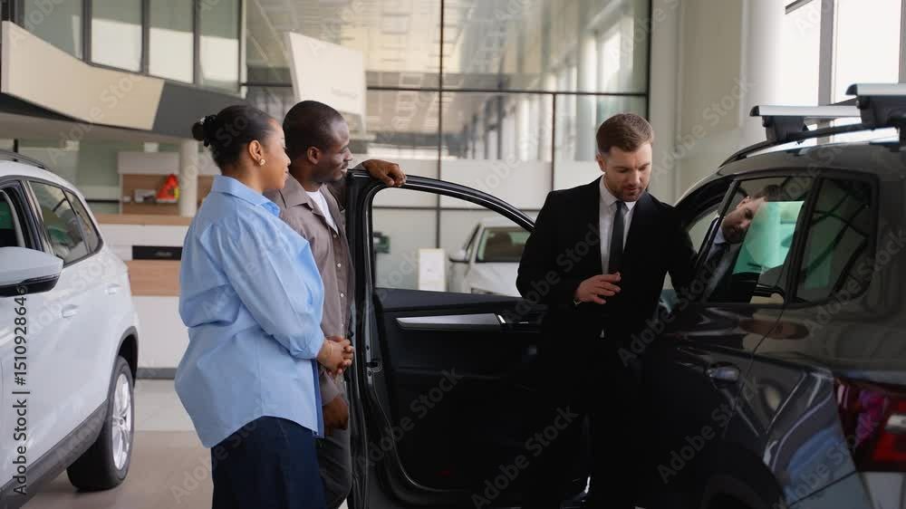 Car salesman showing features of new car to african american couple Car salesman showing features of new car to african american couple
