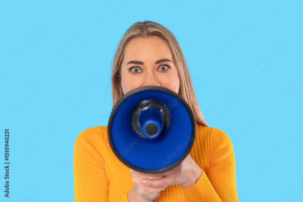 Fototapeta premium Woman holding megaphone and looking directly into the camera against a solid blue background during a vibrant and energetic moment