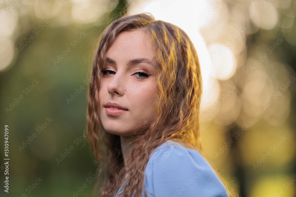 Naklejka premium Beautiful Girl with long hair posing in sunbeams in park