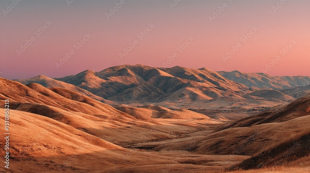 Naklejka premium A panoramic view of a mountain range from atop a hill, with a rosy-pink and azure sky as the backdrop