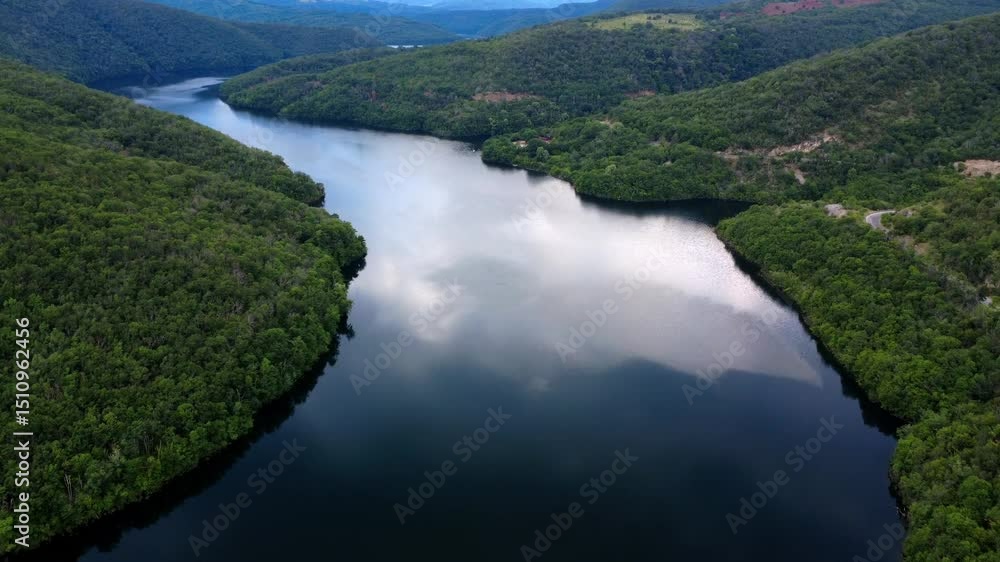 Aerial panoramic view of Ivaylovgrad Reservoir in Bulgaria, surrounded by lush green forests and hills, reflecting the sky in calm waters. Serene nature and scenic landscape captured by drone. Aerial panoramic view of Ivaylovgrad Reservoir in Bulgaria, surrounded by lush green forests and hills, reflecting the sky in calm waters. Serene nature and scenic landscape captured by drone.