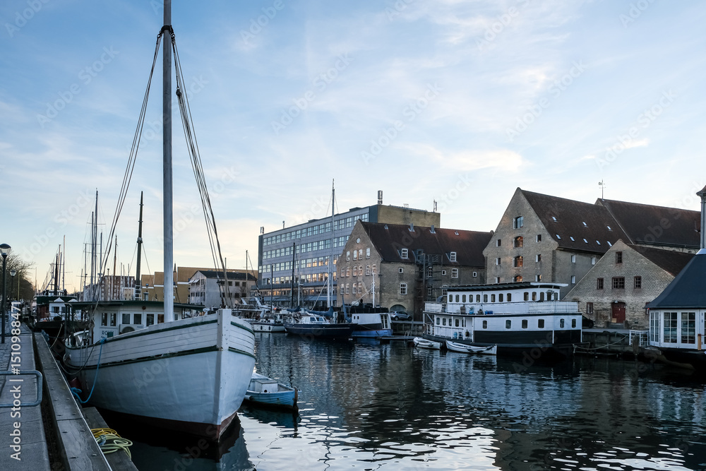 Fototapeta premium Copenhagen – View of Christianshavn Canal, lined with moored boats and colorful houses, reflecting the charm of this picturesque historic neighborhood.