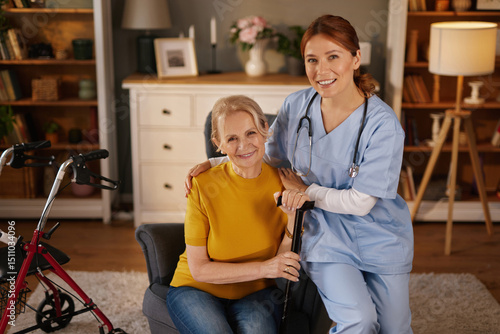 фотографія A caring medical professional supports an elderly woman inside a warm and inviting living room
