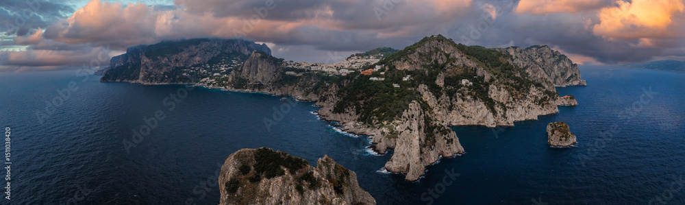 Aerial view of Capri Island near the Amalfi Coast, featuring cliffs, lush greenery, white buildings, sea stacks, and the surrounding blue waters. Aerial view of Capri Island near the Amalfi Coast, featuring cliffs, lush greenery, white buildings, sea stacks, and the surrounding blue waters.