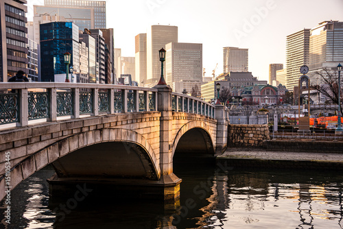 Pucturqesque Barazono bashi bridge in front of towering skyscrapers in golden evening lights. Nakanoshima in Osaka, Japan. A green Island park in the center of Osaka.