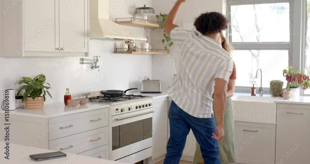 Happy diverse couple dancing together in bright kitchen, enjoying morning routine, at home Happy diverse couple dancing together in bright kitchen, enjoying morning routine, at home