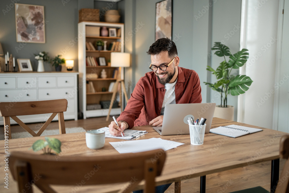 Smiling architect designing new project using laptop at home office Smiling architect designing new project using laptop at home office