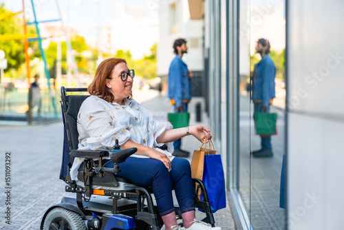 Obraz na płótnie Happy woman in wheelchair doing shopping in a modern city