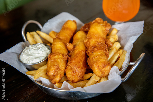 Fish and Chips in a metal bowl with a cocktail 