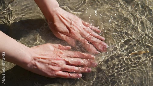 Young woman washing hands in clear mountain river