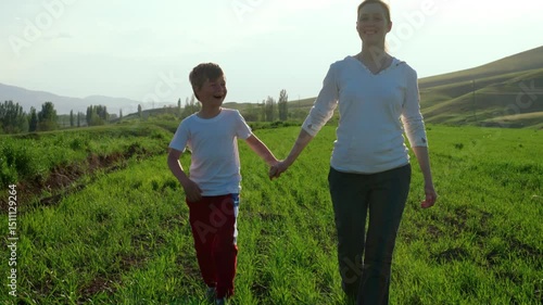Happy mother and son walking on summer field sunny portrait, slow motion