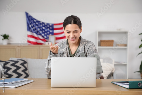 Female soldier with laptop video chatting at home