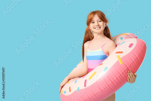 Fotografija Little redhead girl with inflatable ring on blue background