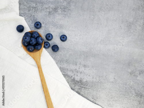 Blueberries in wooden spoon with cloth on stone texture background