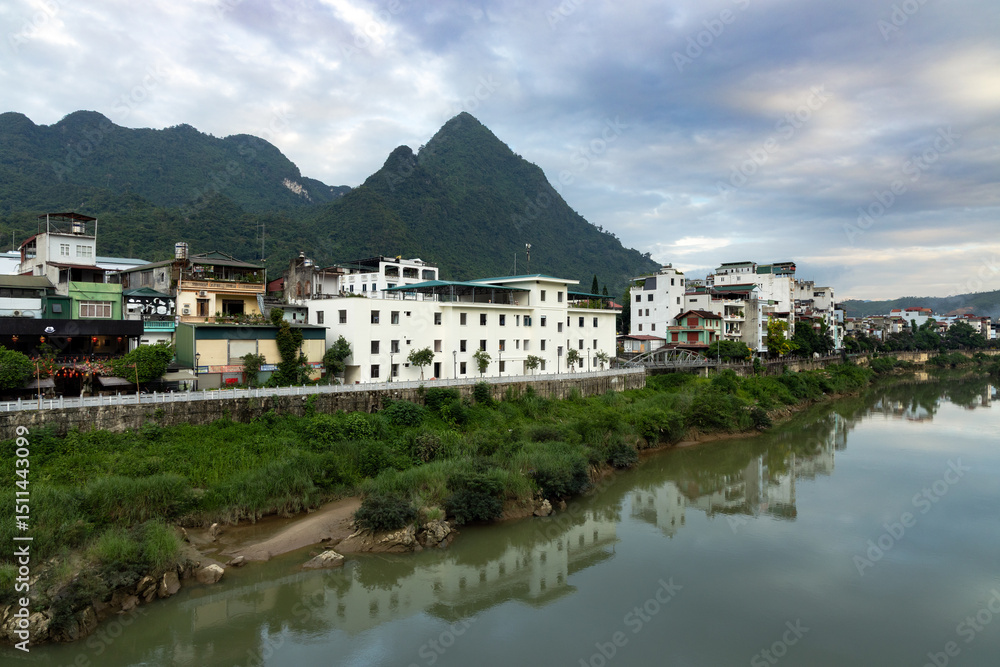 Obraz premium Ha Giang town stretching along the river with forested mountains in the background
