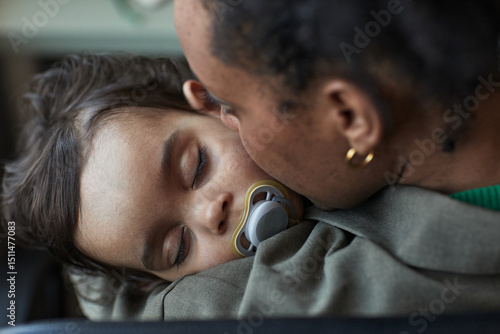 Wallpaper Mural Child sleeping peacefully while being cradled in mother's arms, displaying a tender moment of parental love and affection. Close-up highlights emotional bond between child and parent Torontodigital.ca