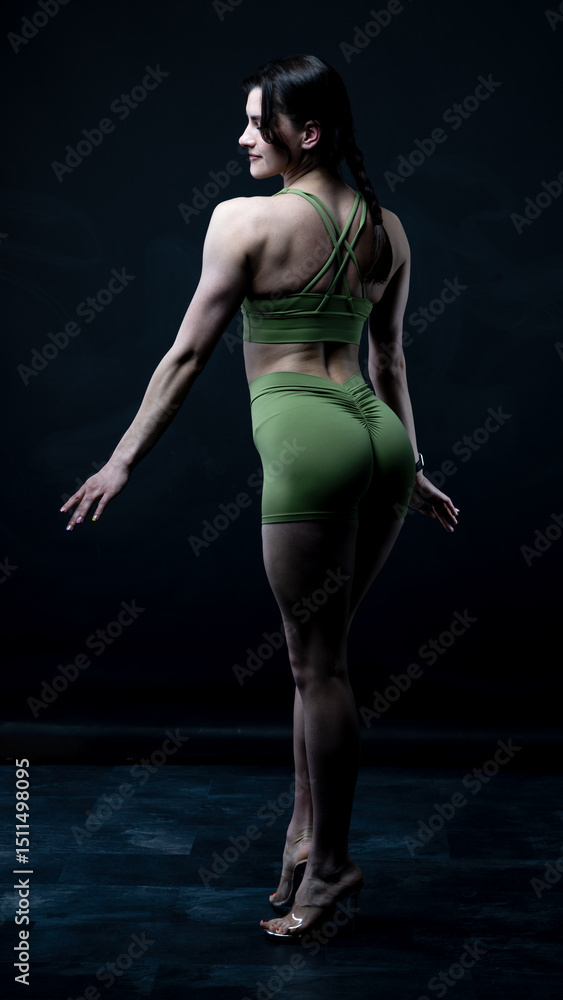Obraz premium Young beautiful woman with athletic body on dark background. Fitness girl 