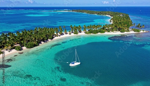 Seascape panorama displaying exotic island with sandy beach and sailboat