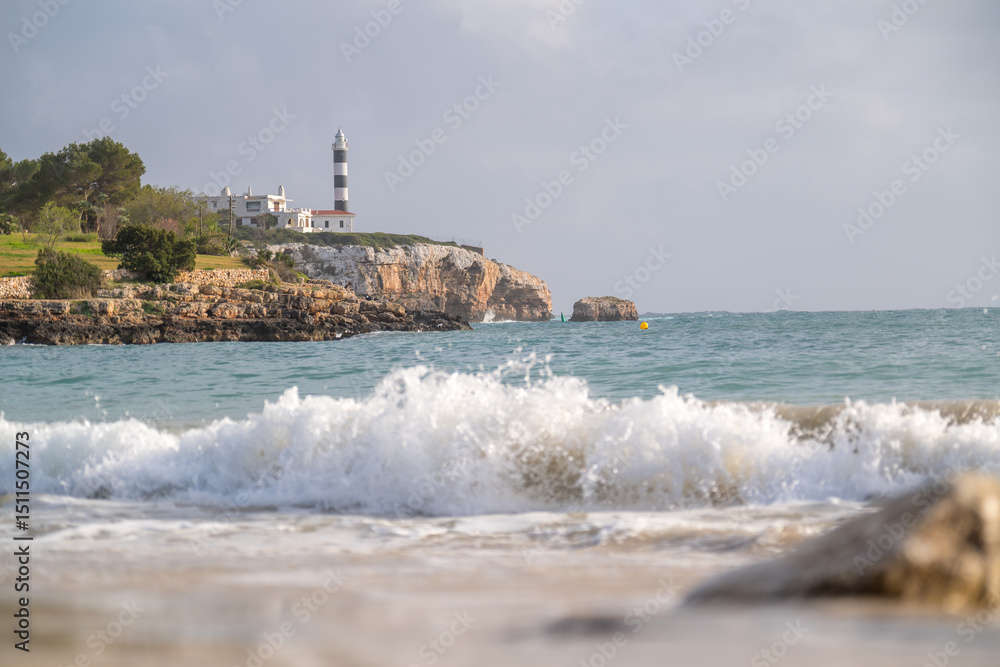 Leuchtturm auf Felsen mit Brandung am Strand Leuchtturm auf Felsen mit Brandung am Strand