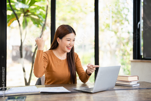 Free Download Startup small business entrepreneur SME of freelance Asian woman using a laptop and cell phone. Cheerful success Asian woman lifts up hand celebrate for online marketing. SME idea concept. - GFXLoad