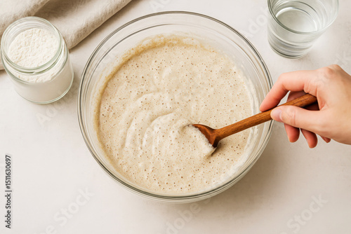 Wallpaper Mural Mixing dough for sourdough bread, in a glass bowl with a wooden spoon, surrounded by flour, water, and a clean kitchen countertop, showcasing the baking preparation process and culinary creativity Torontodigital.ca