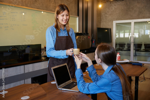 young barista giving a cup of coffee to customer in the cafe