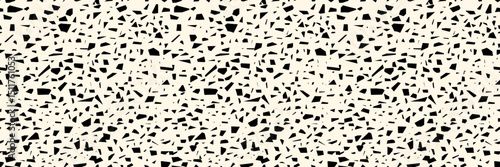 Hand drawn speckle terrazo seamless pattern. Black gritty and fleck texture on beige background. Vector simple backdrop.