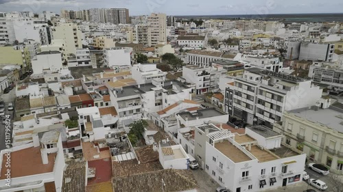 Drone flies over neighborhood in historic city center on cloudy day in Faro, Portugal