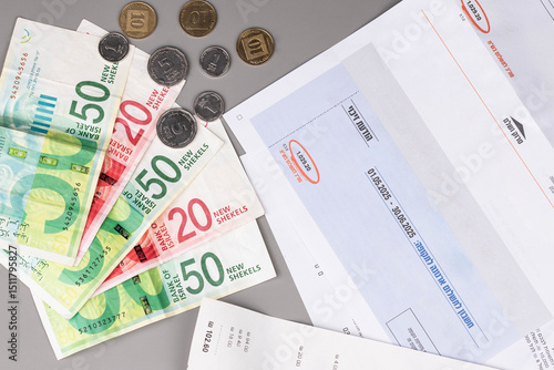 Fotografija Israel currency New Israeli shekel (NIS) banknotes and agorot coins, with bills for electricity, water, and taxes, concept of inflation, economic crisis, rising prices, and financial management
