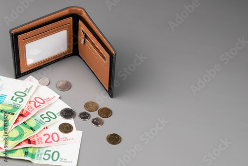 Israel currency New Israeli shekel (NIS) banknotes and agorot coins and empty wallet, concept of saving money, inflation, economic crisis, rising prices, and personal finances.