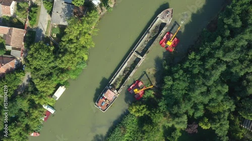 Above top view, dolly move upwards over two excavators dredge as they dredging, working on river, canal, deepening and removing sediment, mud from riverbed in a polluted waterway.