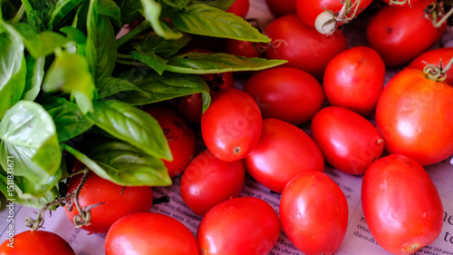 Vibrant red tomatoes beautifully paired with fresh basil leaves, perfect for inspiring your culinary creations