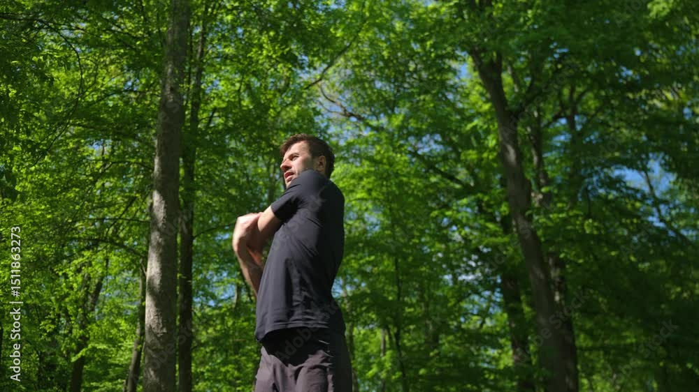 Man in sportswear does warm-up exercises before outdoor workout in sunny park. Concept of healthy lifestyle, fitness and wellness Man in sportswear does warm-up exercises before outdoor workout in sunny park. Concept of healthy lifestyle, fitness and wellness