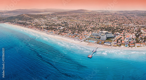 Fototapeta Naklejka Na Ścianę i Meble -  Breathtaking sunset over Ilica beach, Cesme, Turkey, featuring the turquoise Aegean Sea, a sandy beach, captured from an aerial perspective